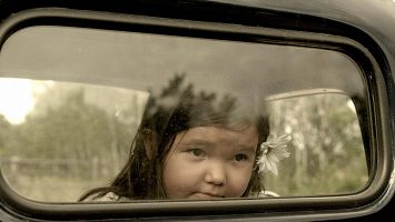Photo : une très jeune fillette autochtone regarde par la fenêtre arrière d'un camion.