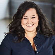 Portrait Manal Drissi : cheveux longs bruns, souriante, chemise bleu marin.